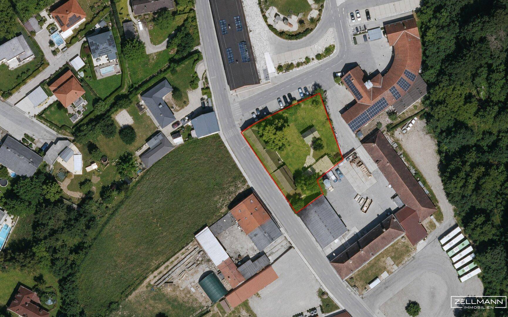 Luftaufnahme eines Grundstücks mit roter Umrandung, umgeben von Straßen und anderen Gebäuden.