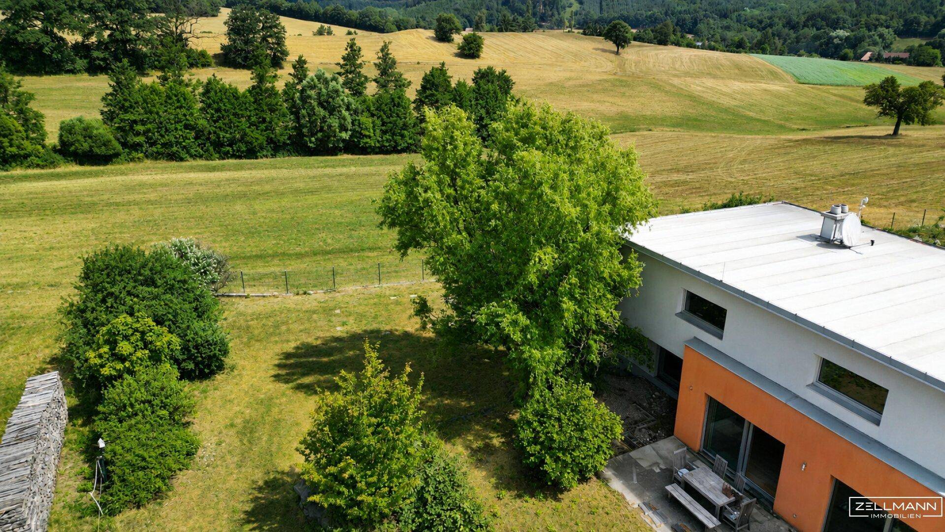 Luftaufnahme des Hauses mit weitläufigem Garten und Blick auf die umliegende grüne Landschaft.