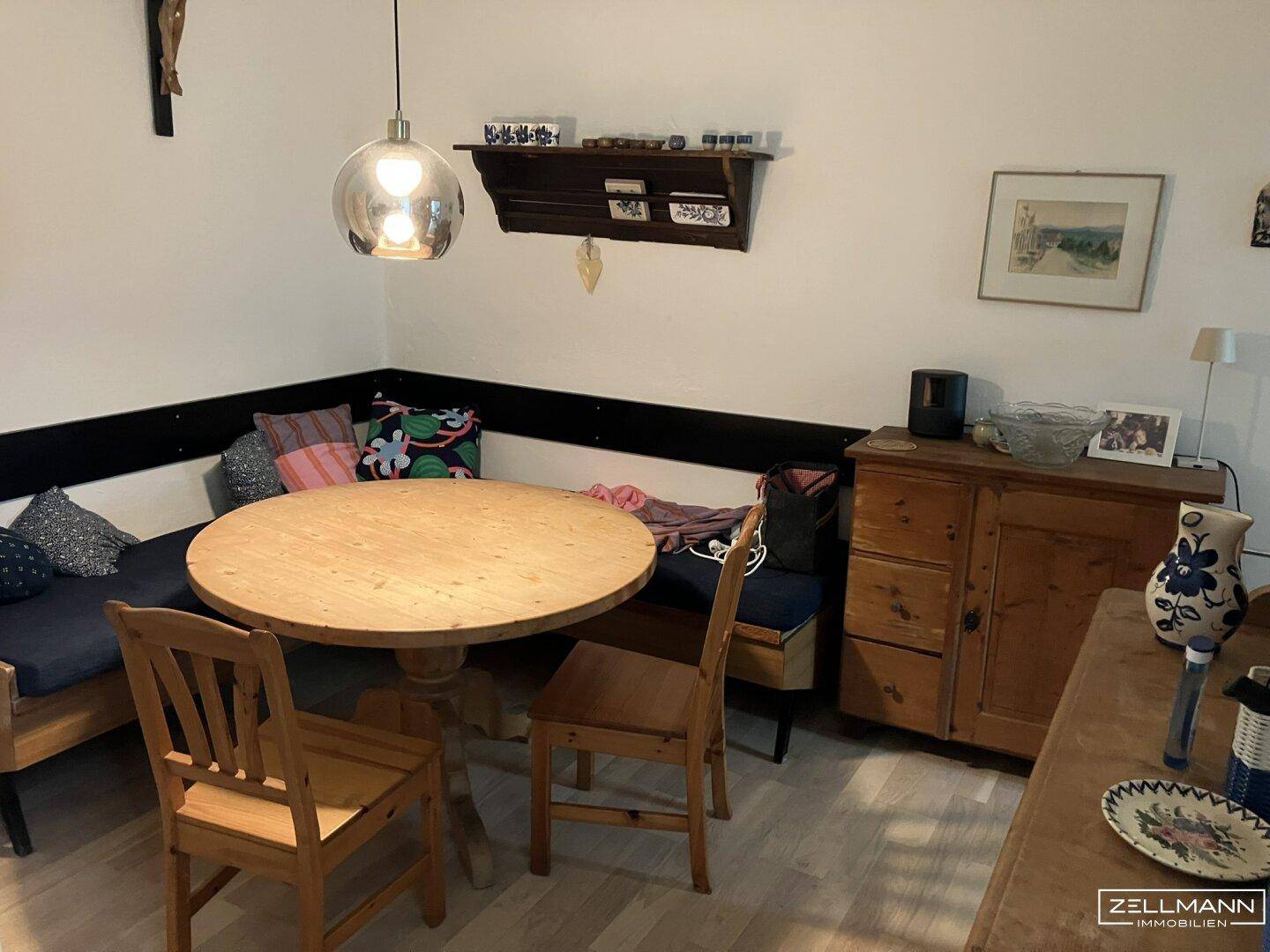 Gemütlicher Essbereich mit rundem Holztisch, Eckbank und traditionellen Holzmöbeln.
