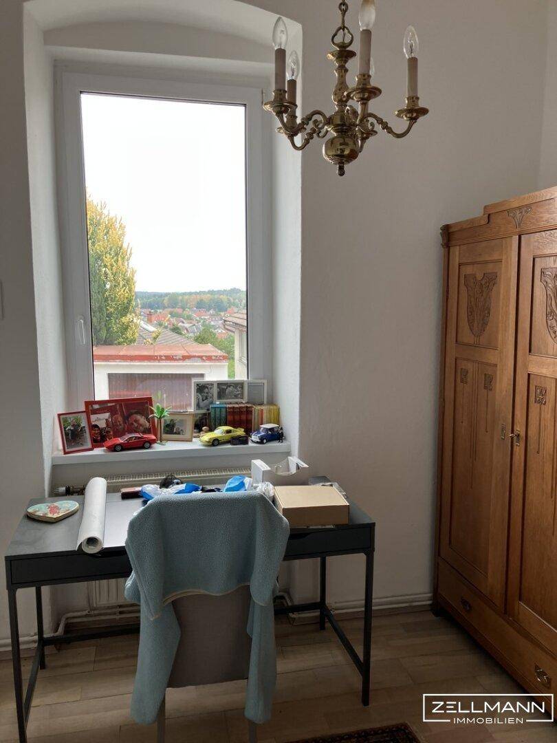 Arbeitszimmer mit Schreibtisch, Holzschrank und einem Fenster mit Blick auf die Umgebung.