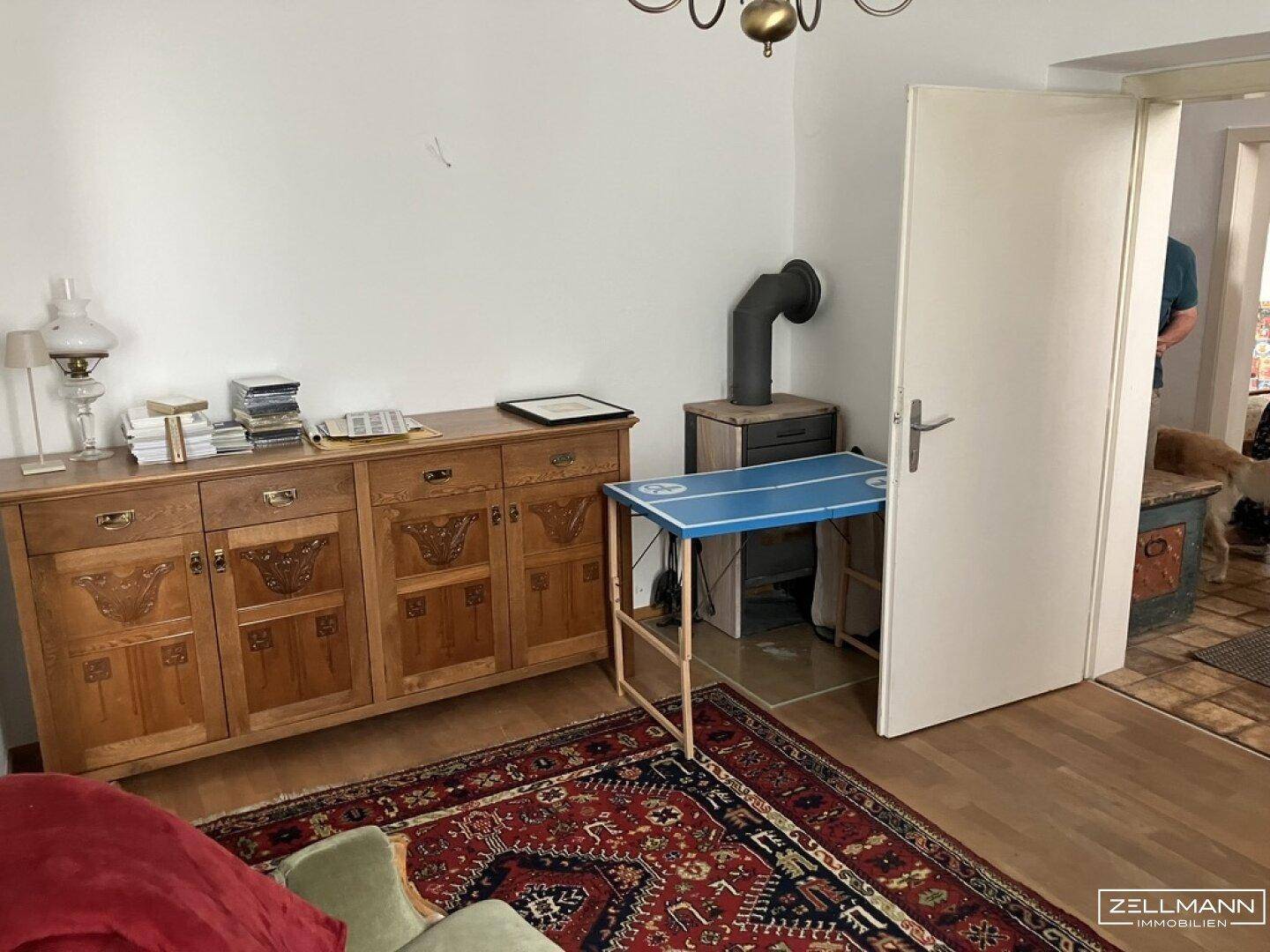 Wohnzimmer mit Holzboden, einem traditionellen Holzschrank und einem Holzofen.