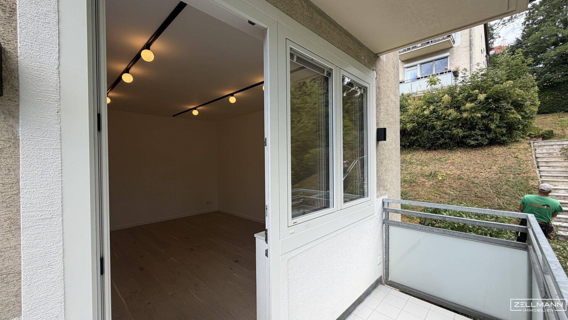 Blick vom Balkon in ein helles Zimmer mit Holzboden und moderner Beleuchtung.