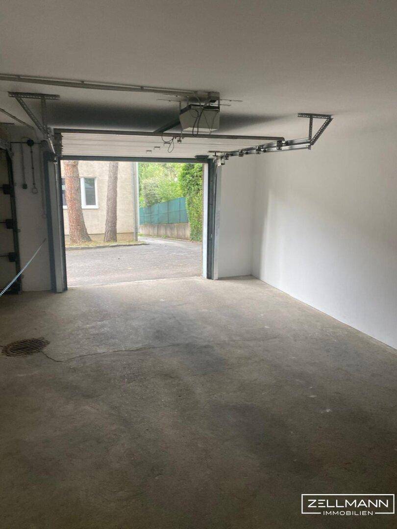 Geräumige Garage mit offenem Tor und Blick auf die Zufahrt im Freien.