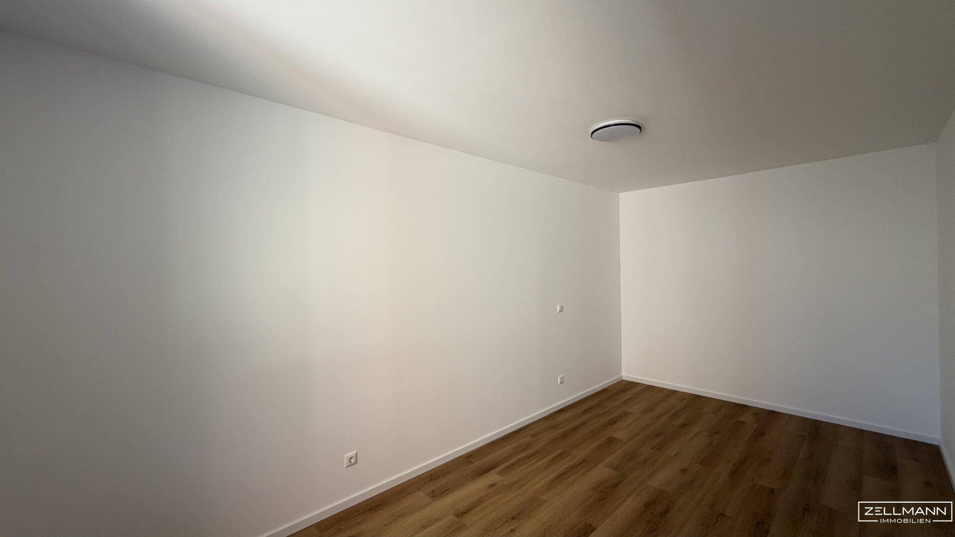 Leeres Zimmer mit hellem Holzboden und weißen Wänden, bereit zur individuellen Gestaltung.