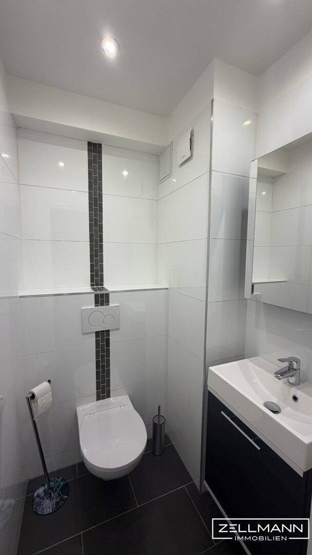 Modernes Gäste-WC mit Wand-WC und Waschbecken, in schlichtem Design.
