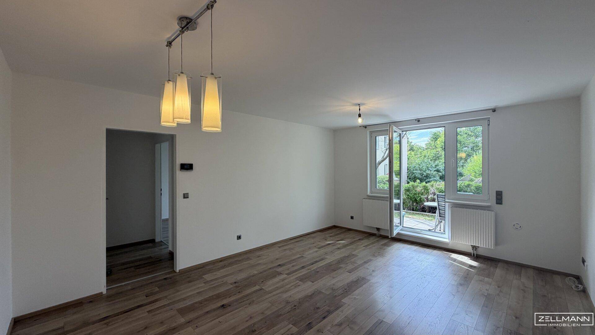 Geräumiges Wohnzimmer mit Holzboden und direktem Zugang zu einem Außenbereich.