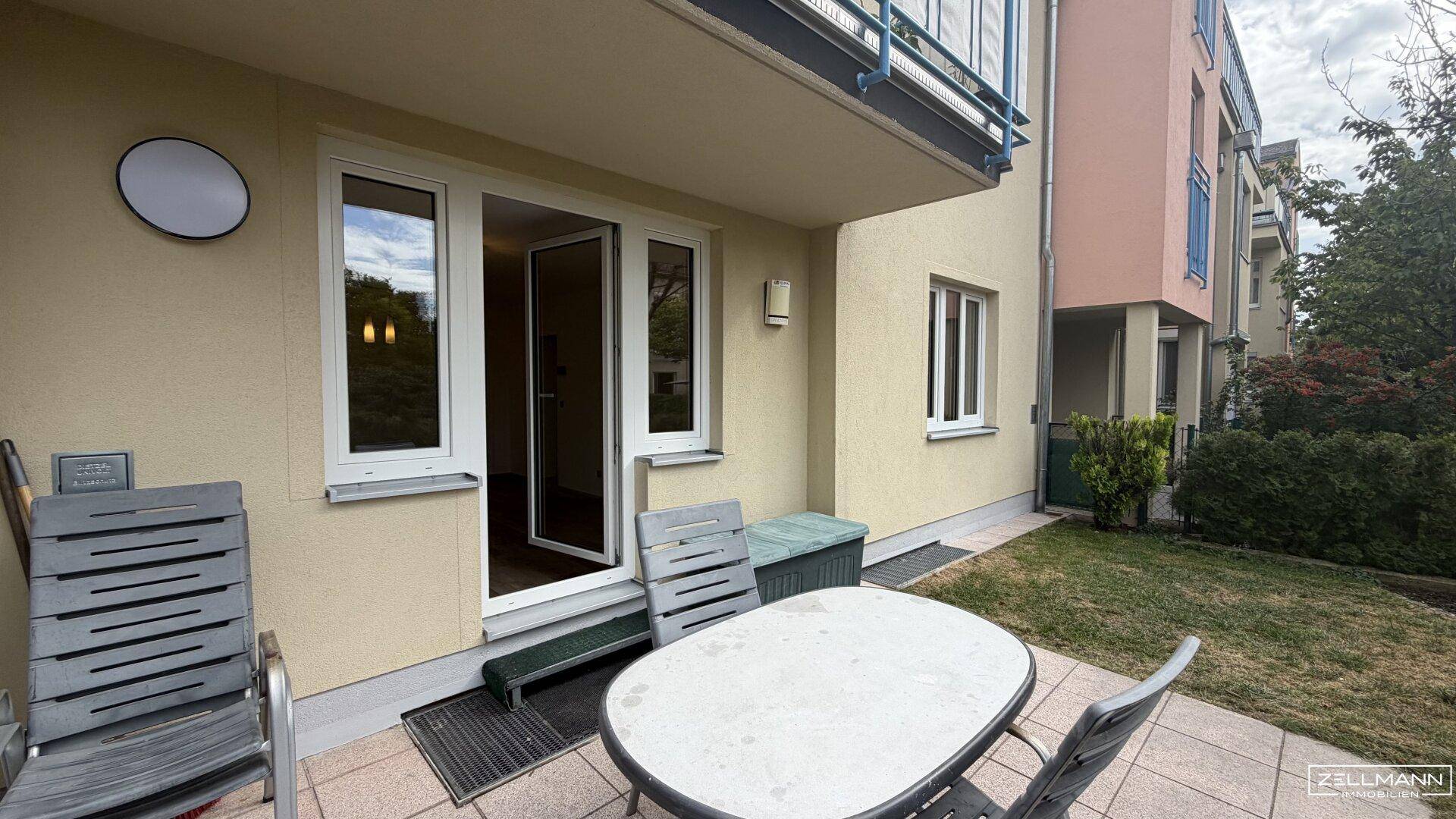 Terrasse mit Sitzgelegenheiten und Blick auf den Garten und das Gebäude.