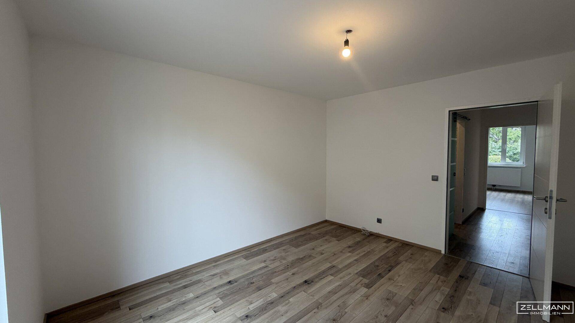 Schlafzimmer mit Holzboden und viel Tageslicht, bereit zur individuellen Gestaltung.