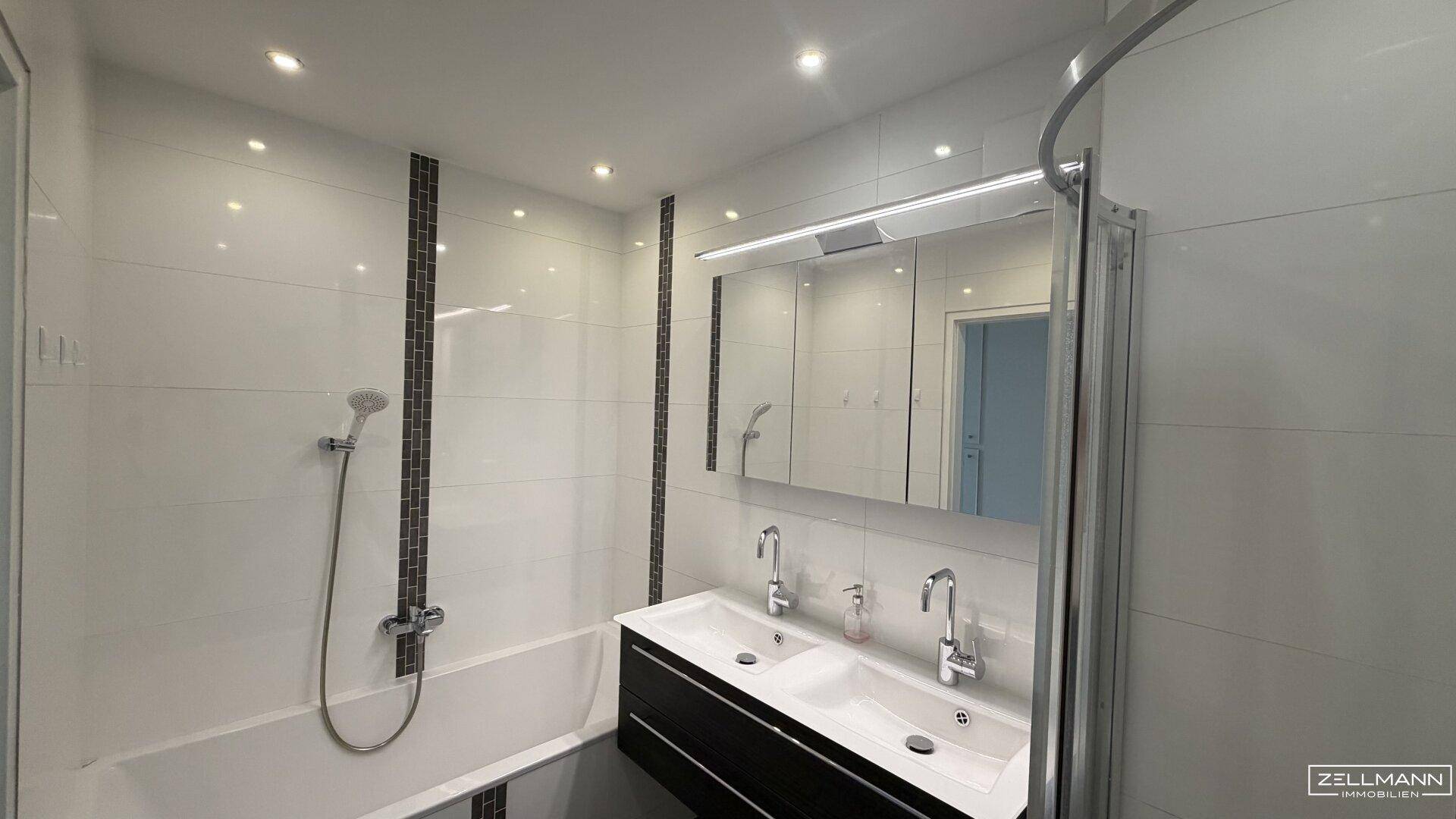 Modernes Badezimmer mit Badewanne, Duschfunktion und Doppelwaschbecken.