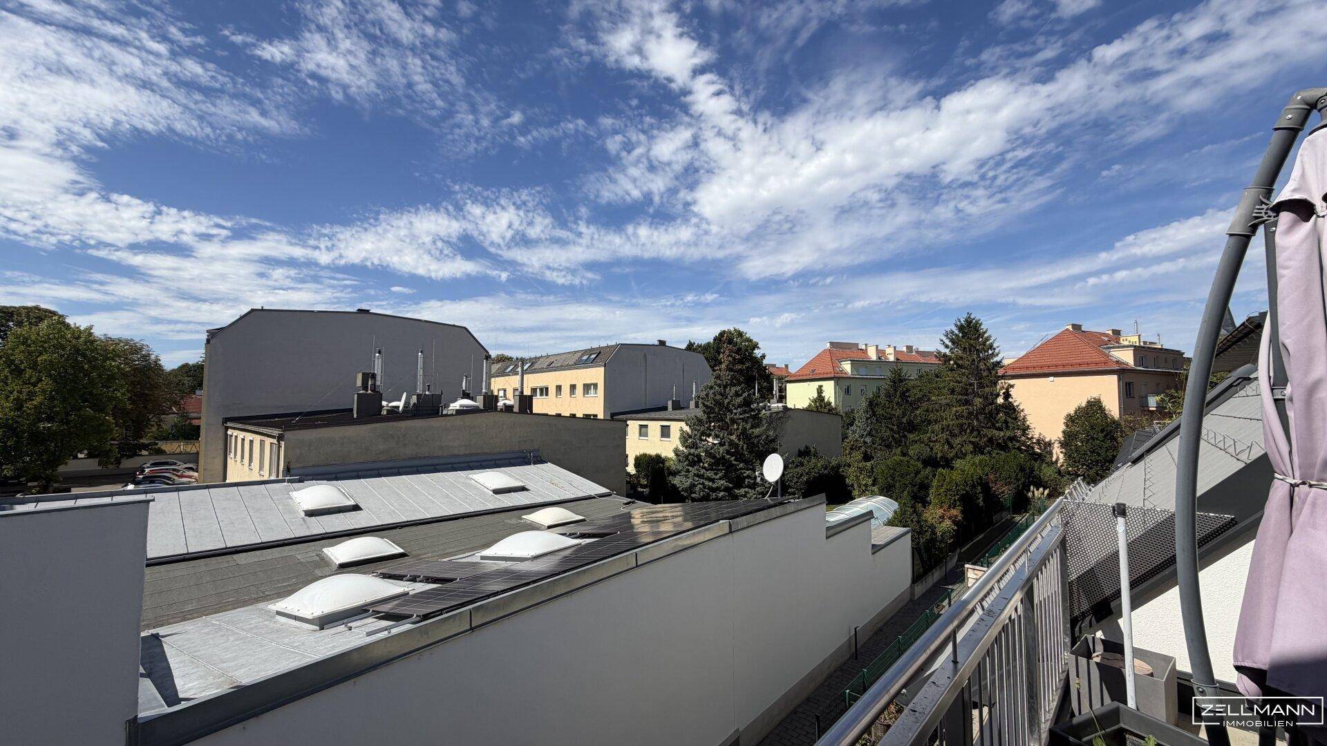 Weitläufiger Blick über die Dächer der Stadt mit blauem Himmel und vereinzelten Wolken.