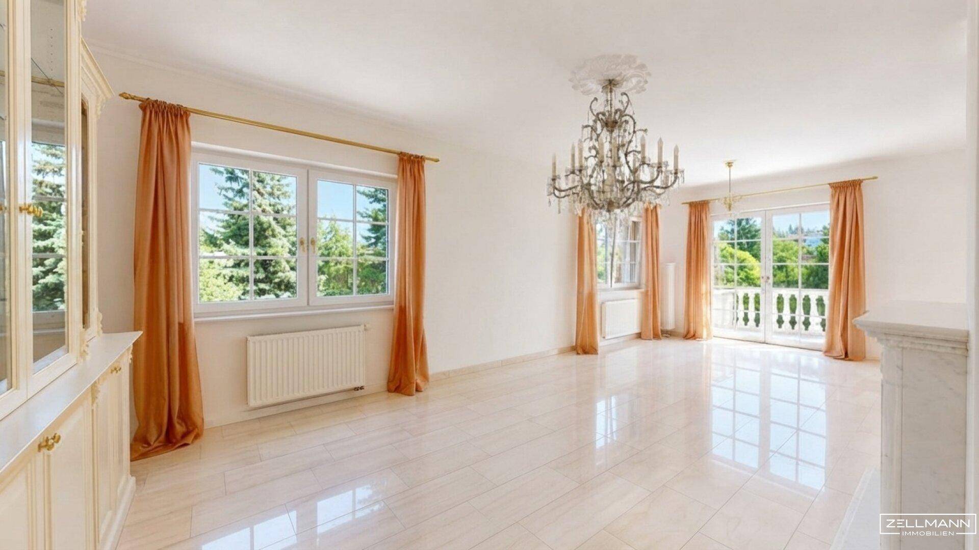 Geräumiges Wohnzimmer mit Stuckdecke, Kronleuchter und Blick ins Grüne.