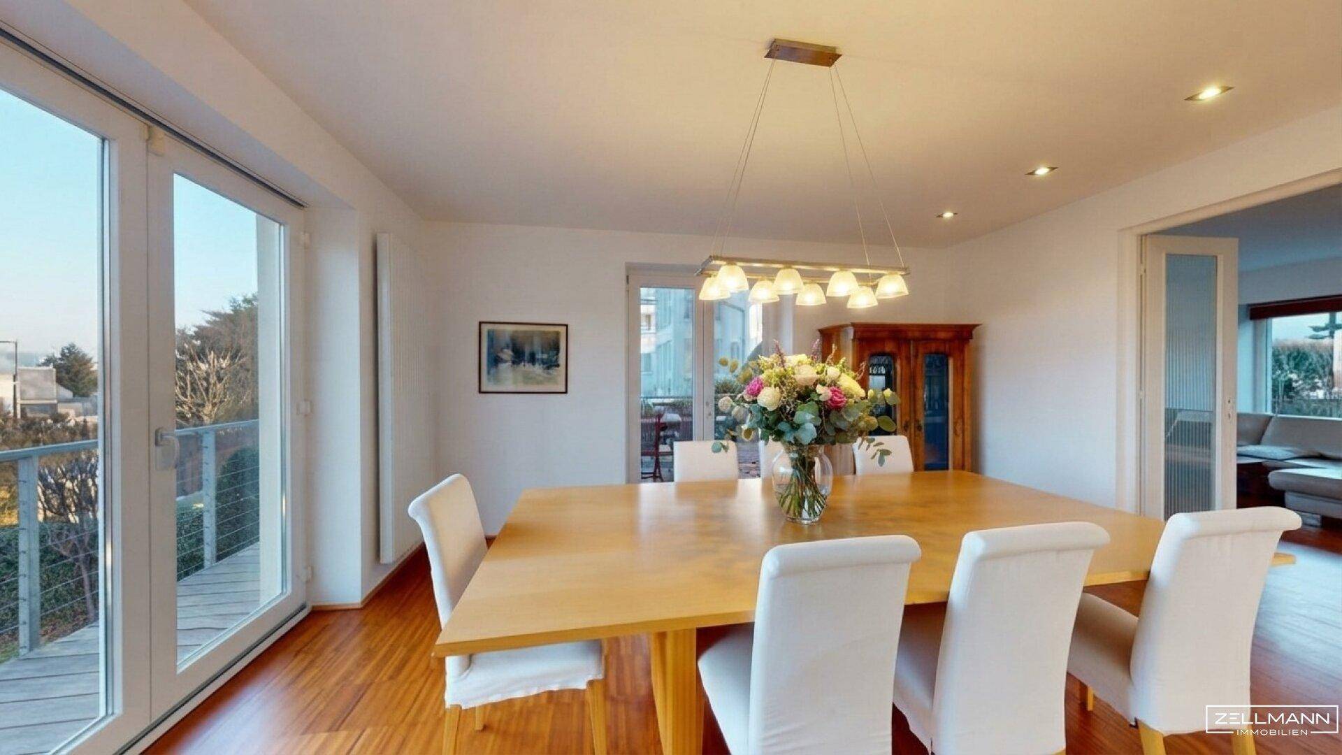 Heller Essbereich mit Holztisch, weißen Stühlen und Zugang zu einem Balkon.