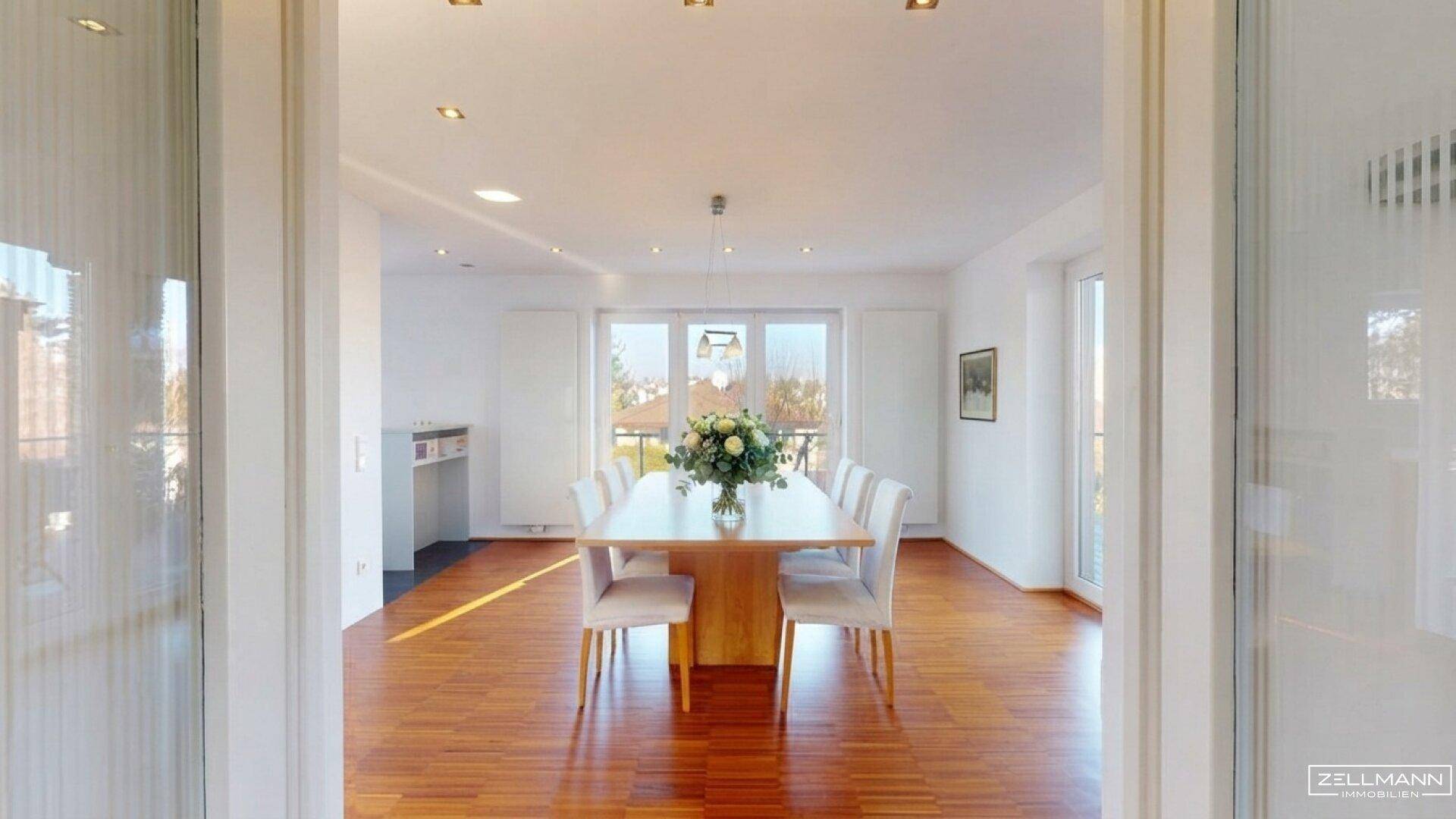 Eleganter Essbereich mit Holzboden und viel Tageslicht durch große Fenster.