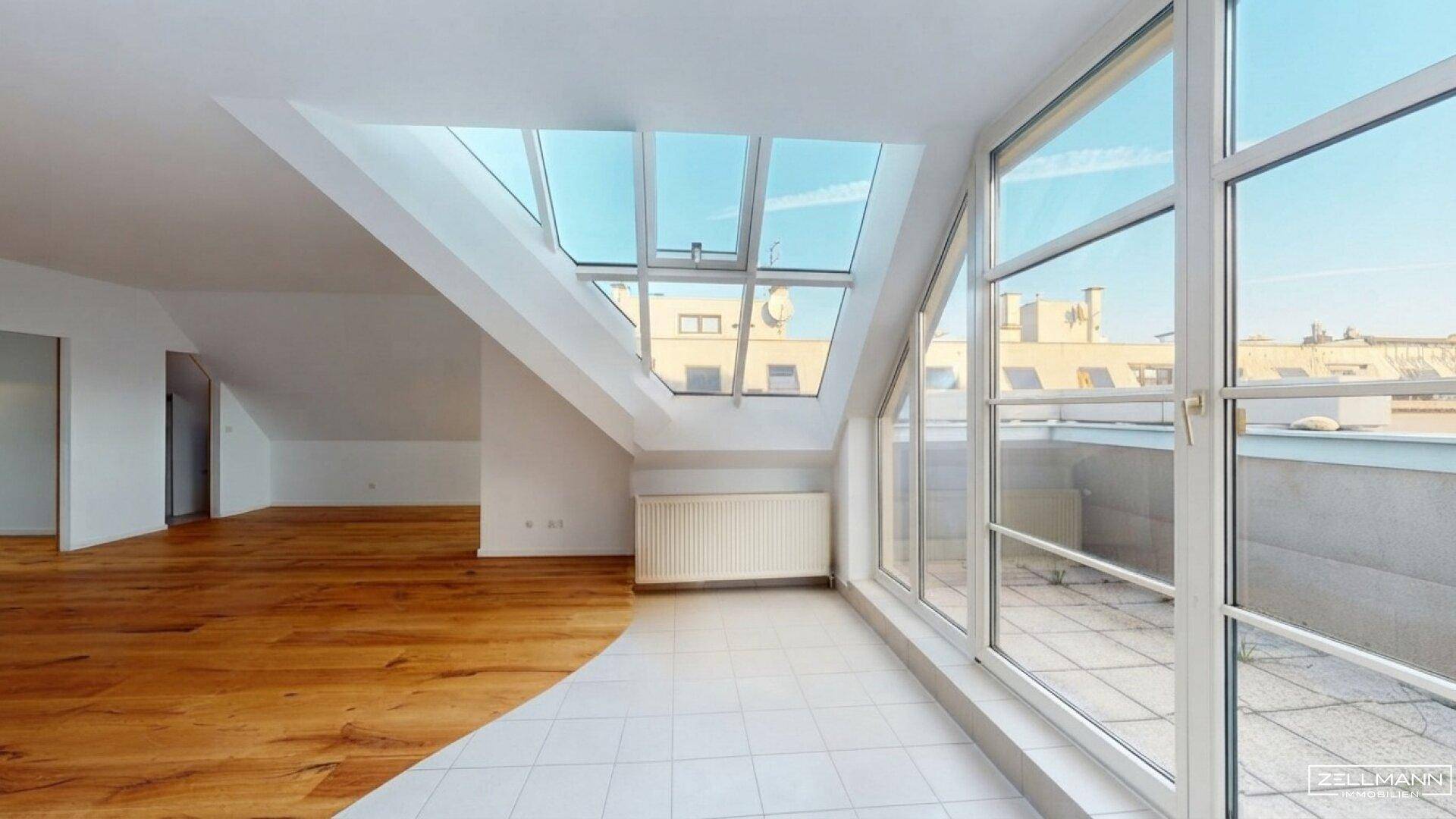 Lichtdurchfluteter Dachgeschossraum mit großen Fenstern und Zugang zu einer geräumigen Dachterrasse.