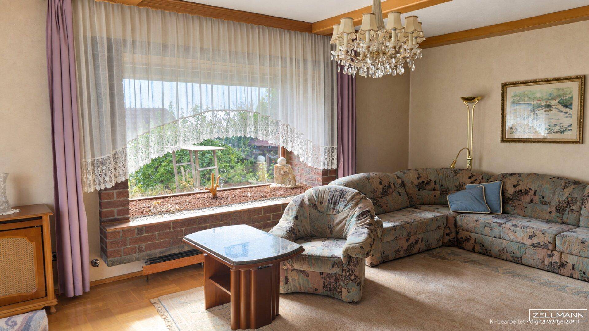 Gemütliches Wohnzimmer mit großem Fenster, bequemer Sofagarnitur und einem eleganten Kronleuchter.