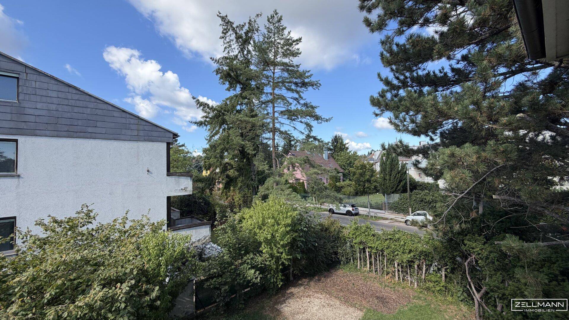 Ausblick auf grüne Bäume, eine ruhige Straße und umliegende Gebäude von der Immobilie.
