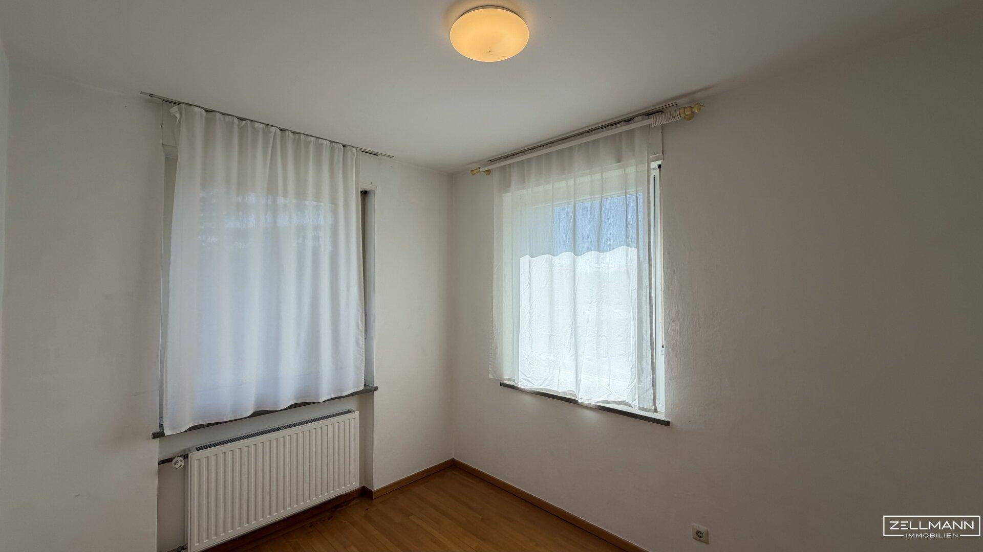 Kleines, helles Zimmer mit Parkettboden und zwei Fenstern, ideal als Kinder- oder Gästezimmer.