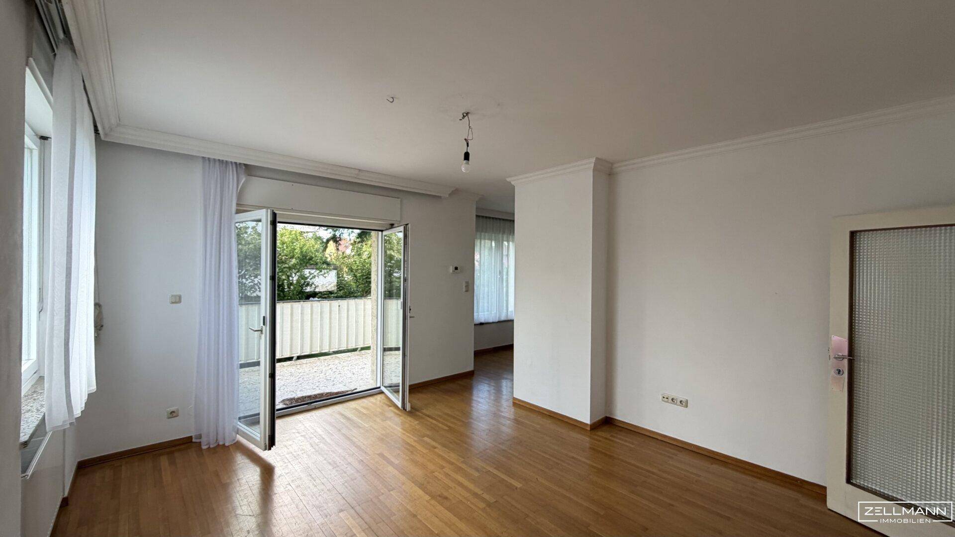Geräumiges Wohnzimmer mit Parkettboden und direktem Zugang zum Außenbereich.