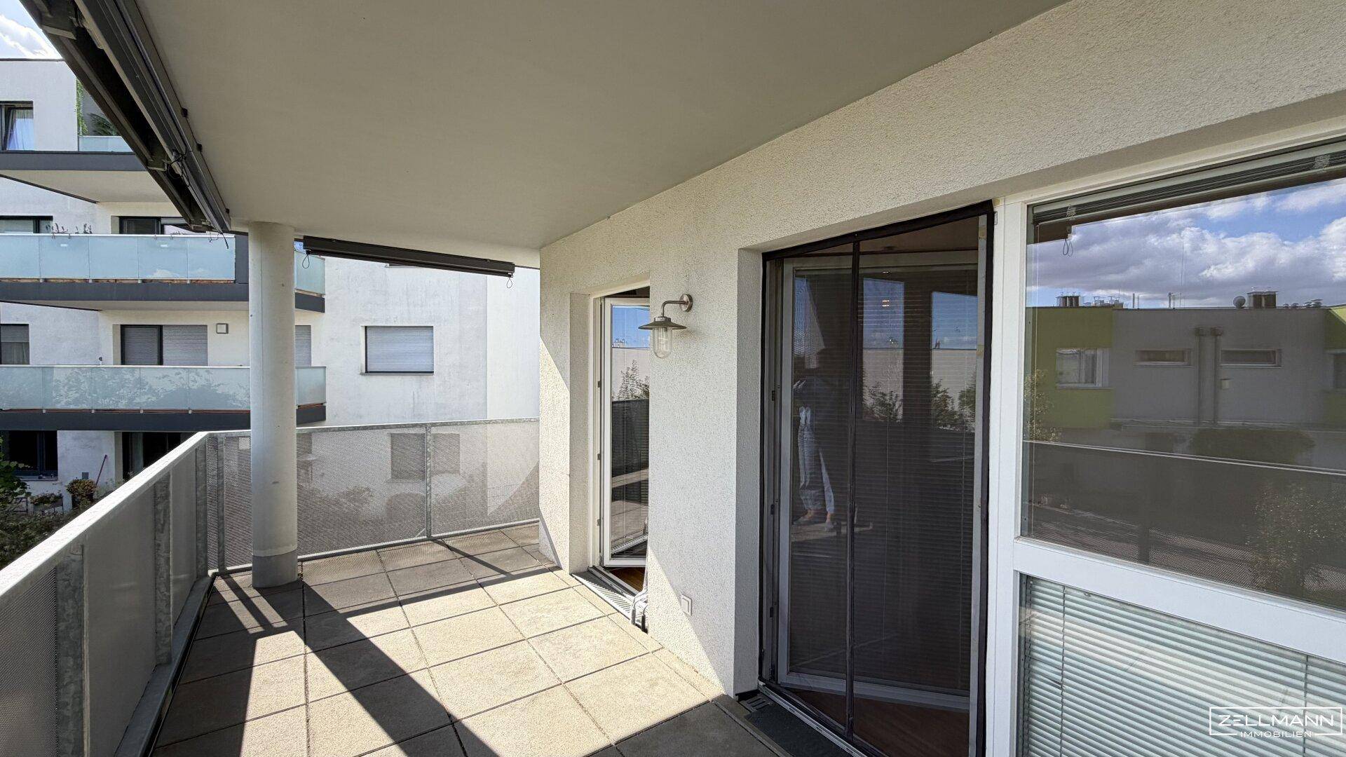 Geräumiger Balkon mit Fliesenboden und Blick auf die umliegenden Gebäude, ideal für Entspannung im Freien.