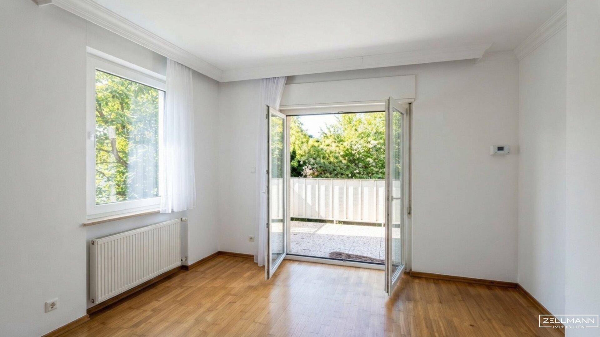 Lichtdurchfluteter Raum mit Holzboden und großem Fenster, das viel Tageslicht hereinlässt.