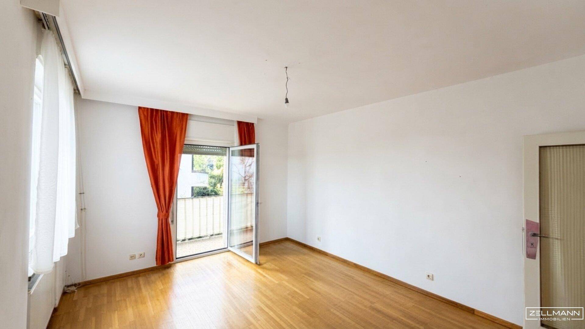 Geräumiges Zimmer mit Holzboden und Zugang zu einem Balkon, ideal als Schlafzimmer.