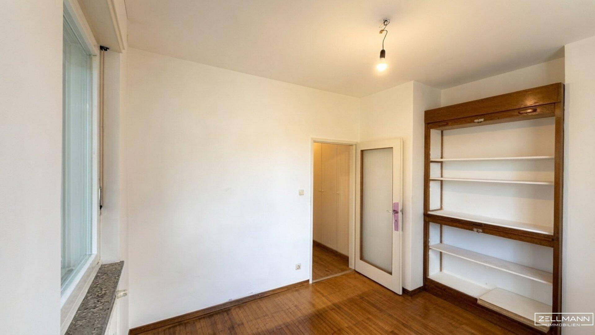 Vielseitiger Raum mit Holzboden und eingebautem Regal, ideal als Büro oder Gästezimmer.