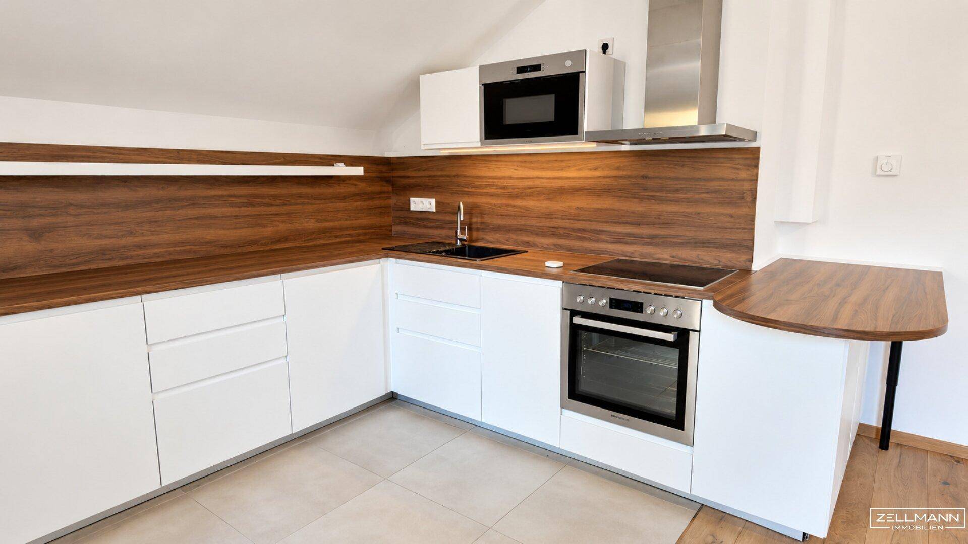 Moderne Einbauküche mit weißen Schränken, Holz-Arbeitsplatten und integrierten Geräten.