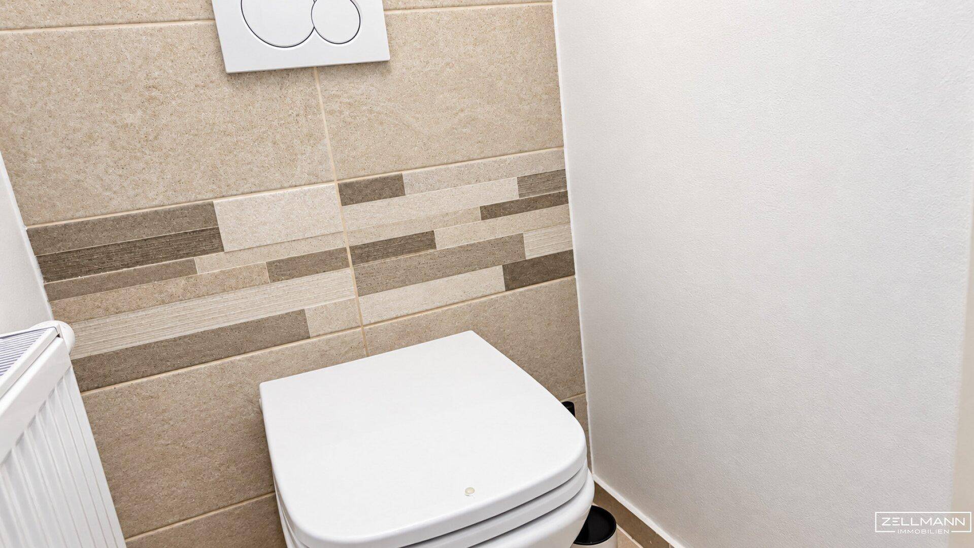 Separates Gäste-WC mit wandhängender Toilette und modernen beigefarbenen Fliesen.