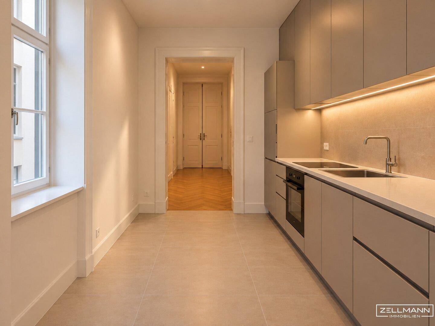 Moderne Küche mit grauen Schränken, integrierten Geräten und Fliesenboden.