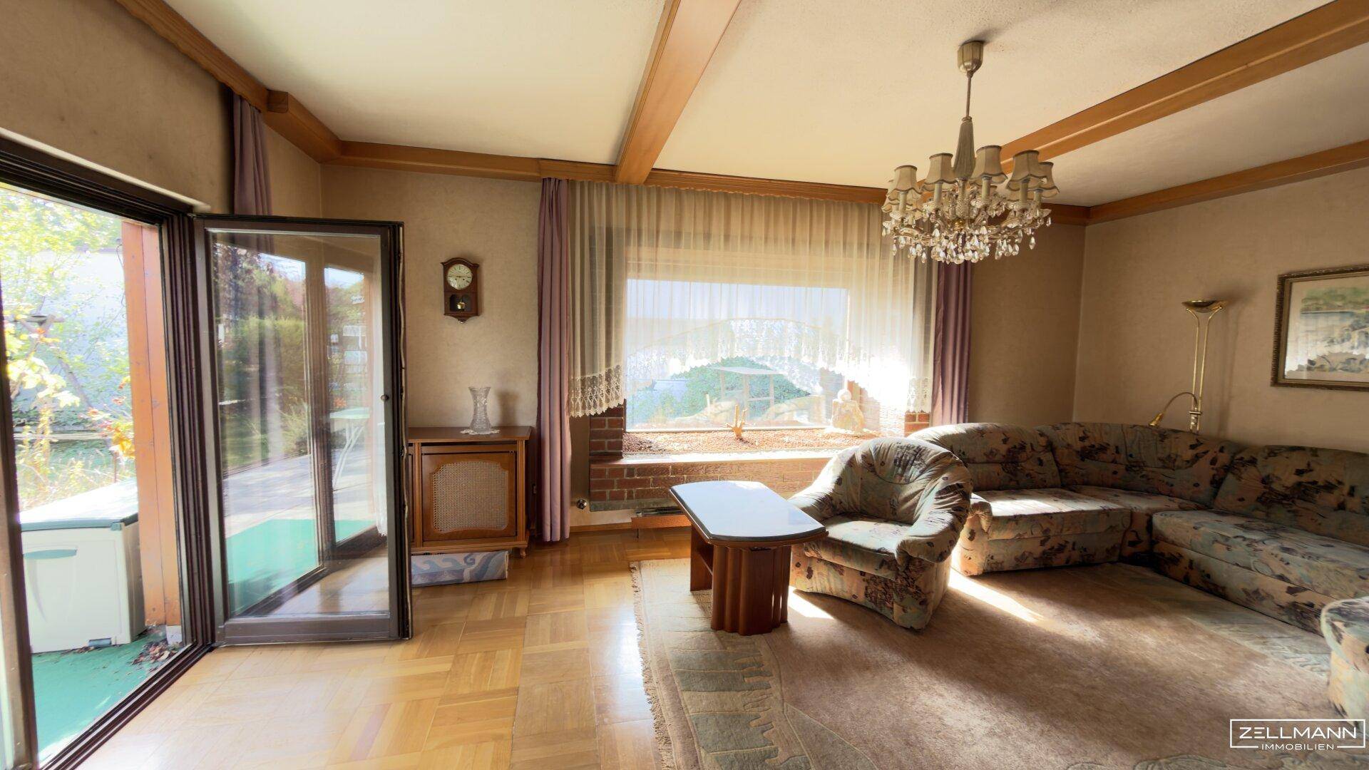 Helles Wohnzimmer mit Zugang zu einem Außenbereich, traditionellen Möbeln und einem Kronleuchter.