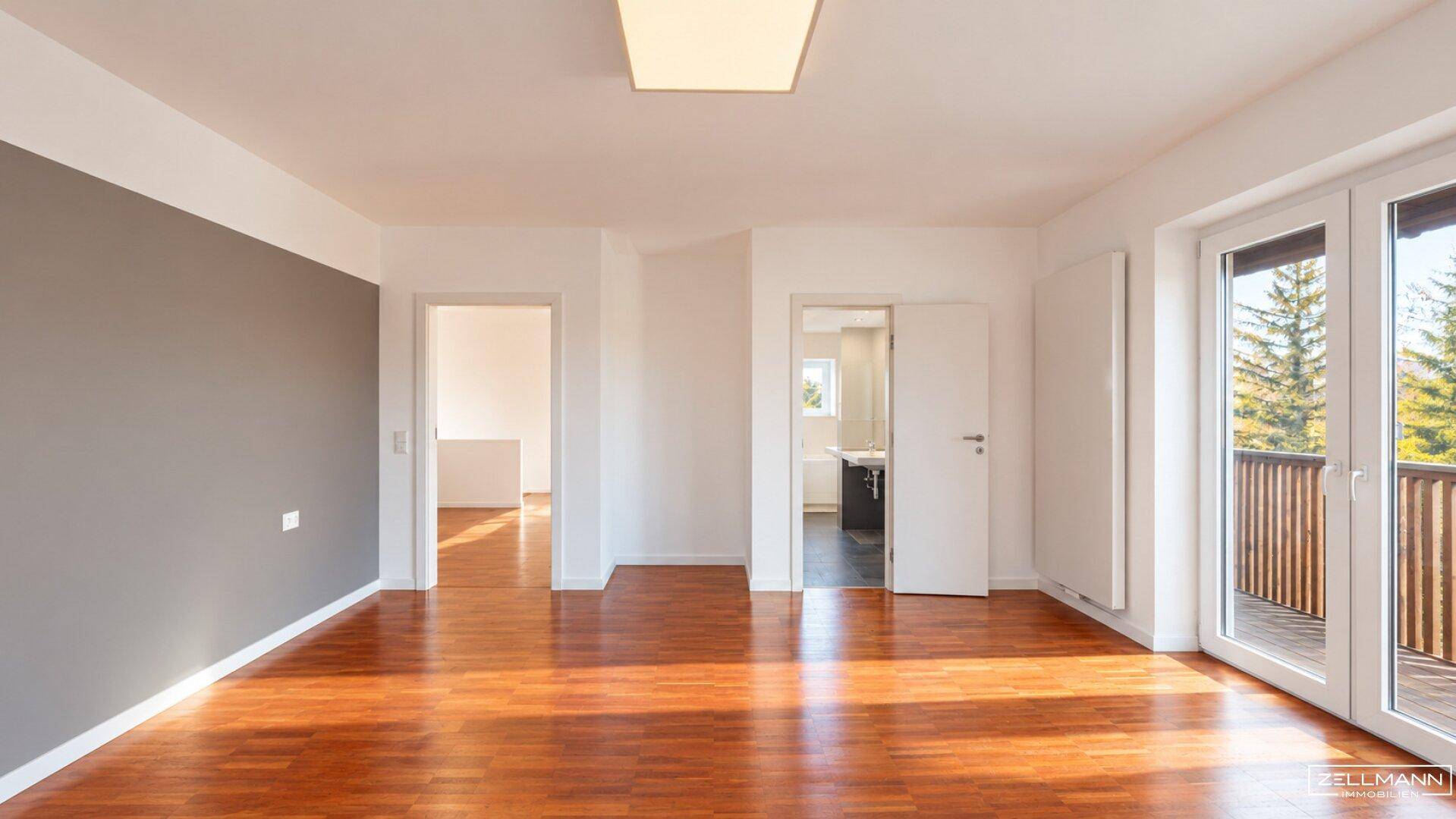 Geräumiges Schlafzimmer mit Parkettboden und Zugang zu einem Balkon.
