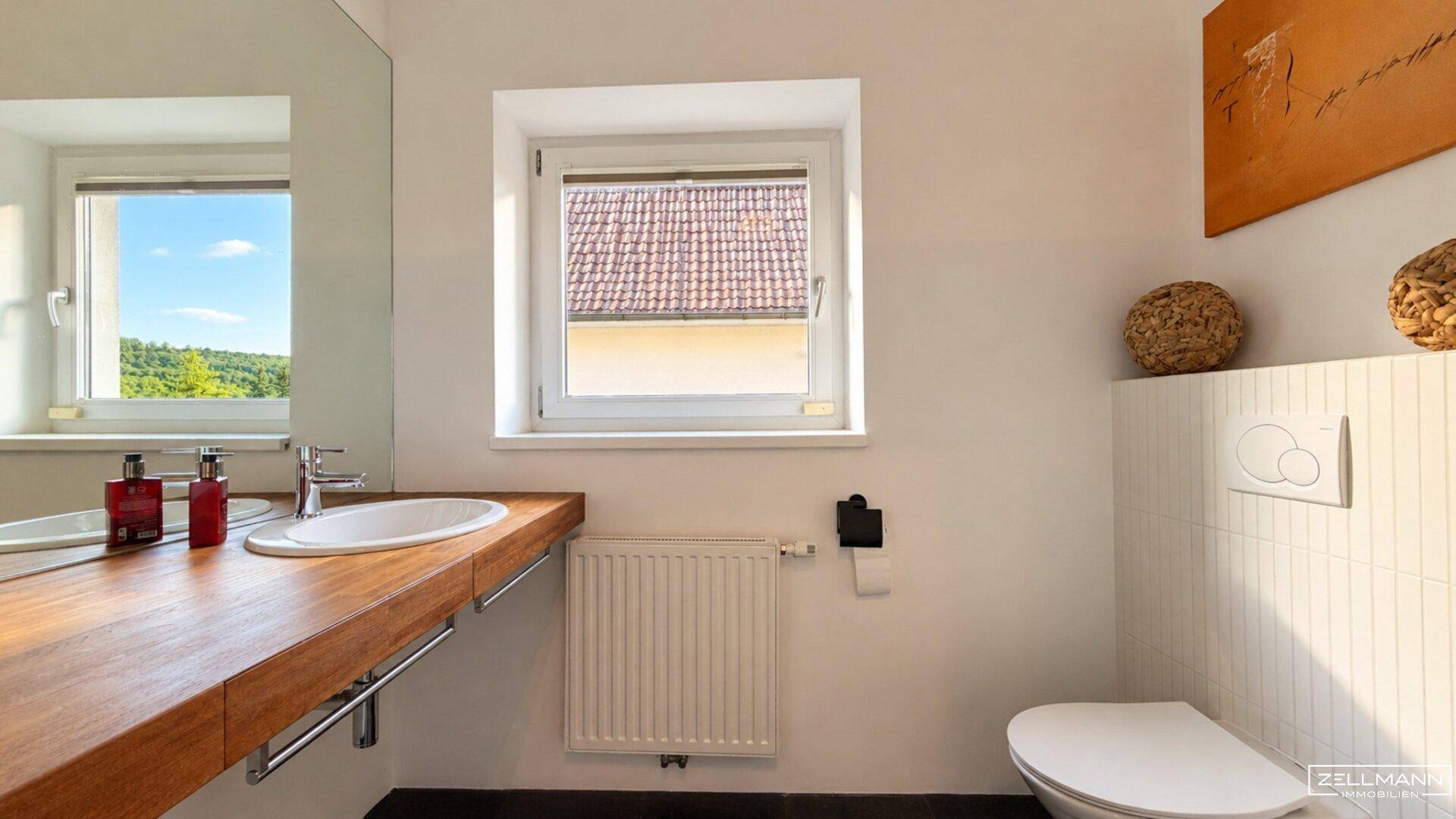 Modernes Badezimmer mit Holzwaschtisch, wandhängendem WC und Fenster.