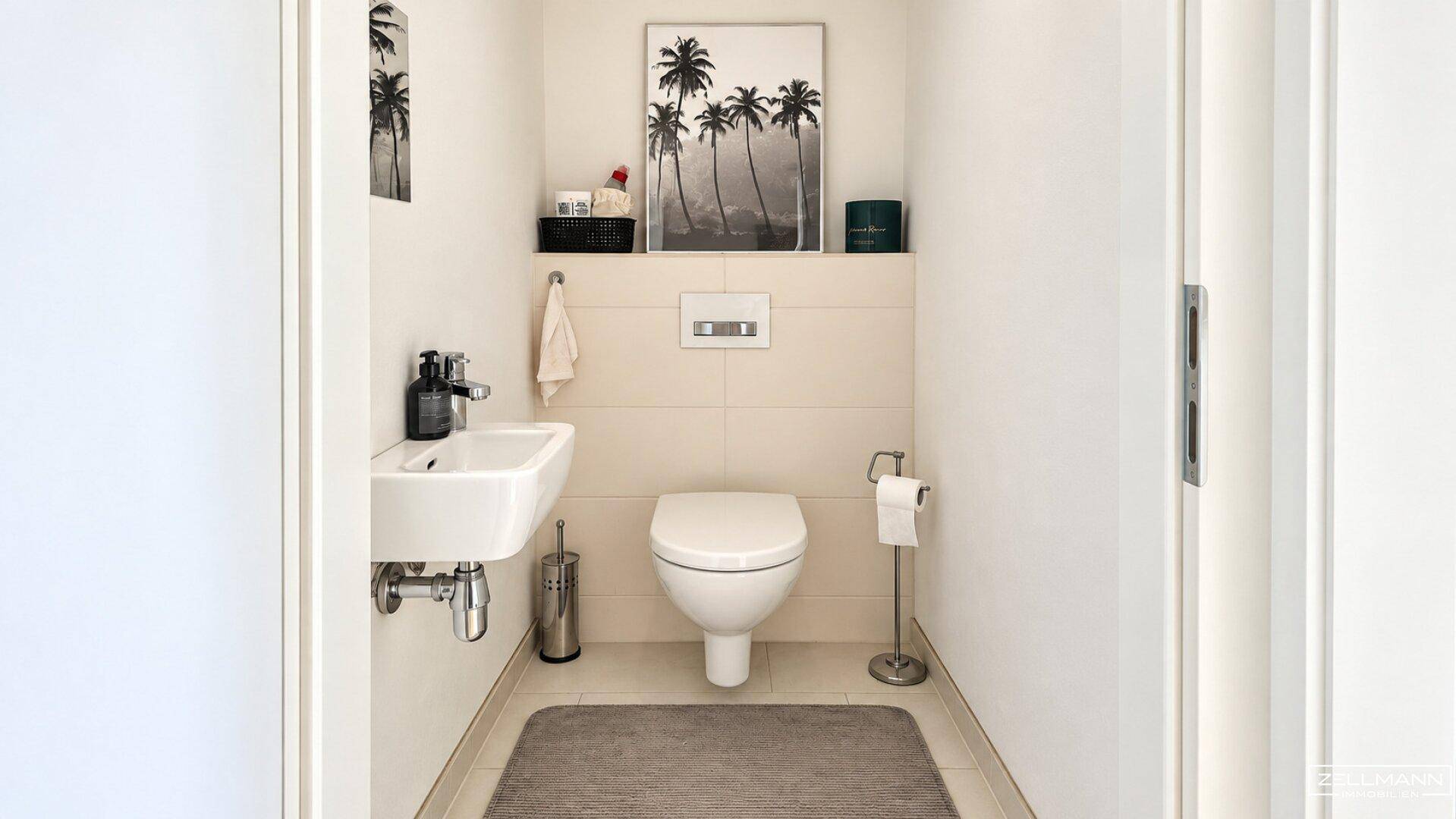Modernes Gäste-WC mit wandhängender Toilette, kleinem Waschbecken und hellen Fliesen.