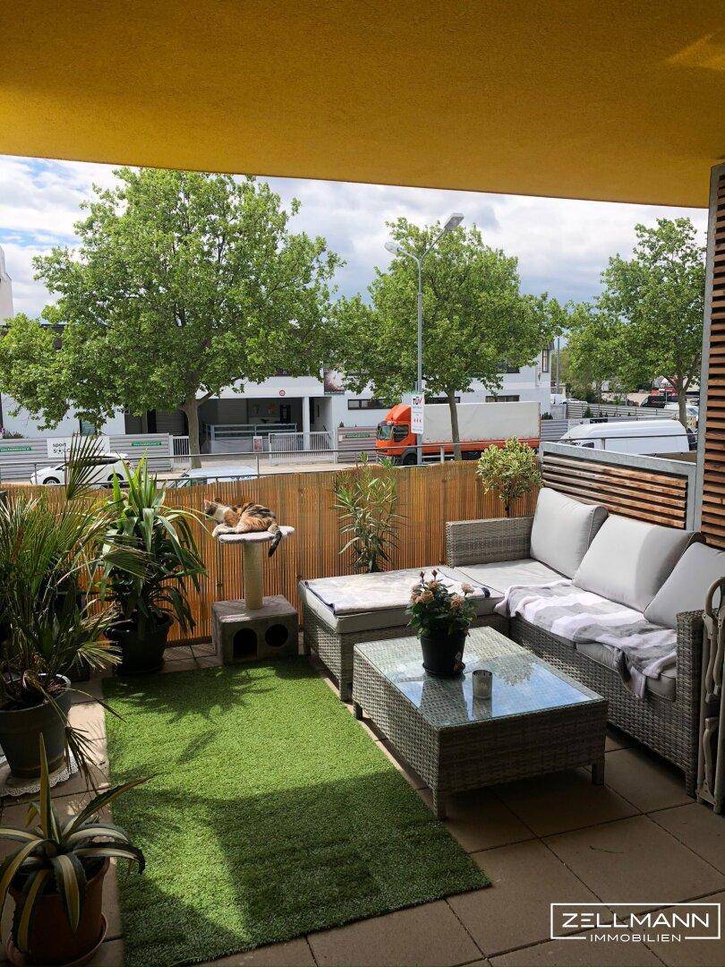 Möblierter Balkon mit Kunstrasen, Pflanzen und gemütlicher Sitzecke für entspannte Stunden.