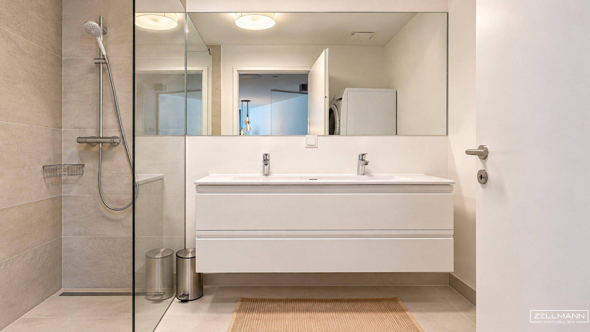 Modernes Badezimmer mit bodengleicher Dusche, Doppelwaschbecken und großem Spiegel.