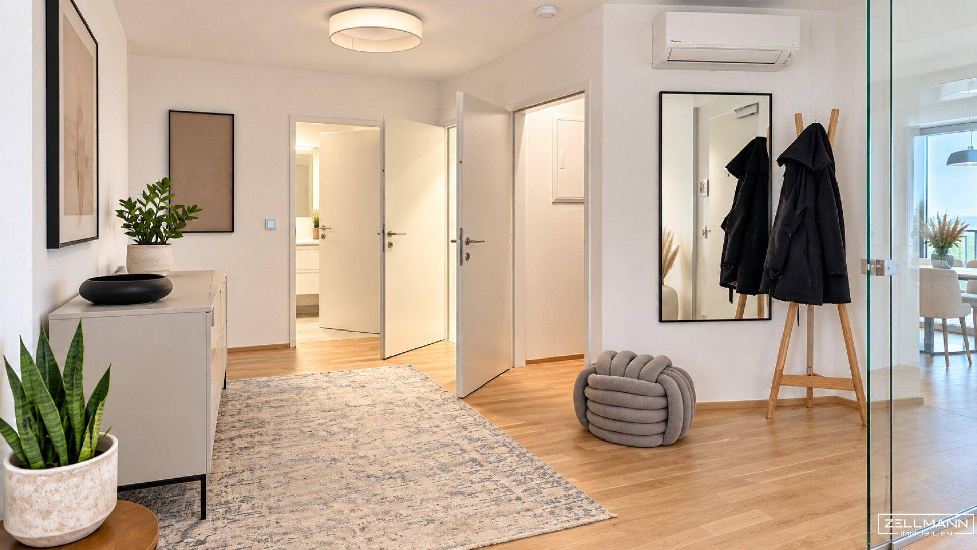 Geräumiger Eingangsbereich mit Holzboden, Spiegel und Garderobe.