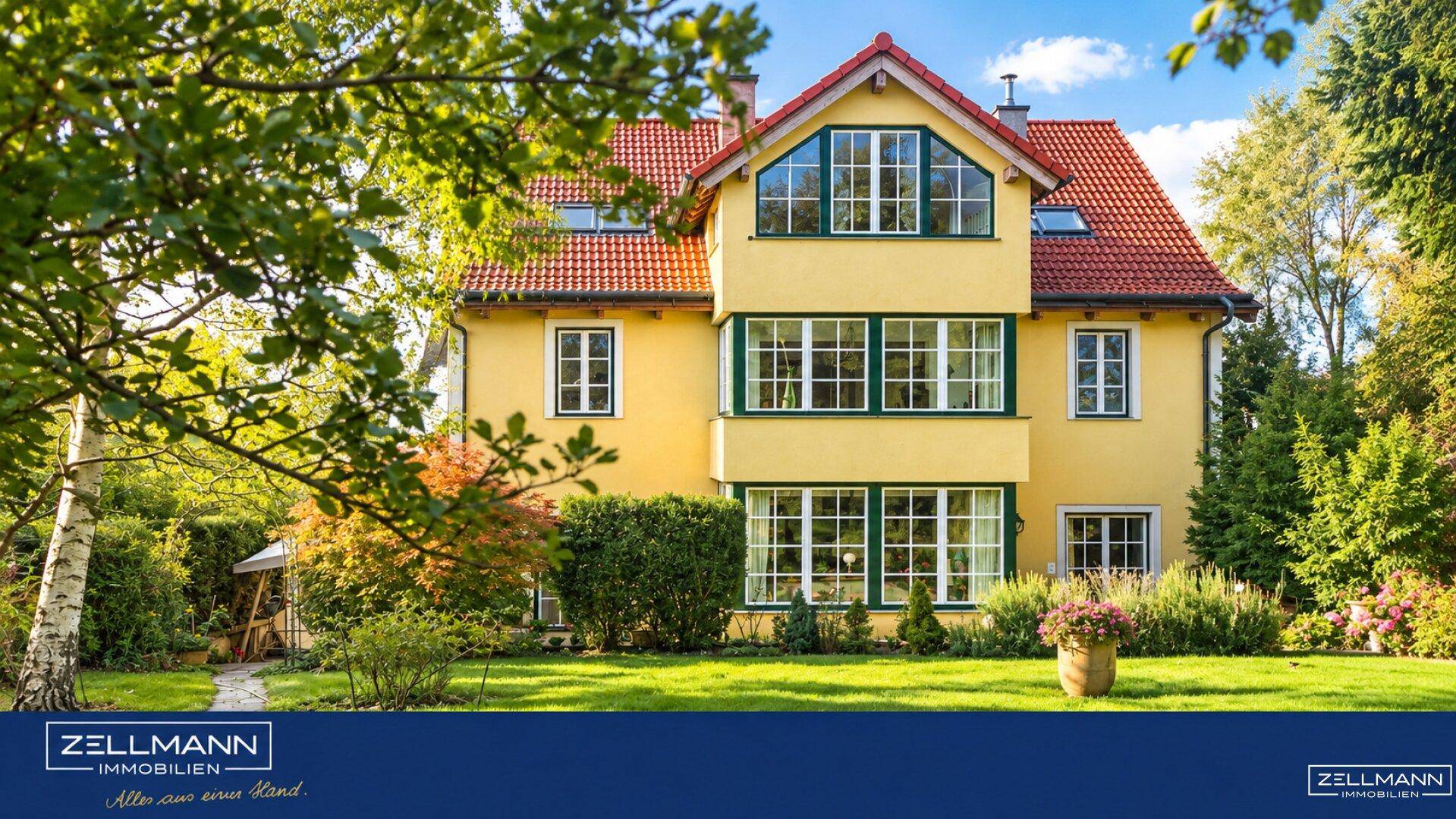 Charmantes gelbes Haus mit roten Ziegeldächern und gepflegtem Vorgarten.