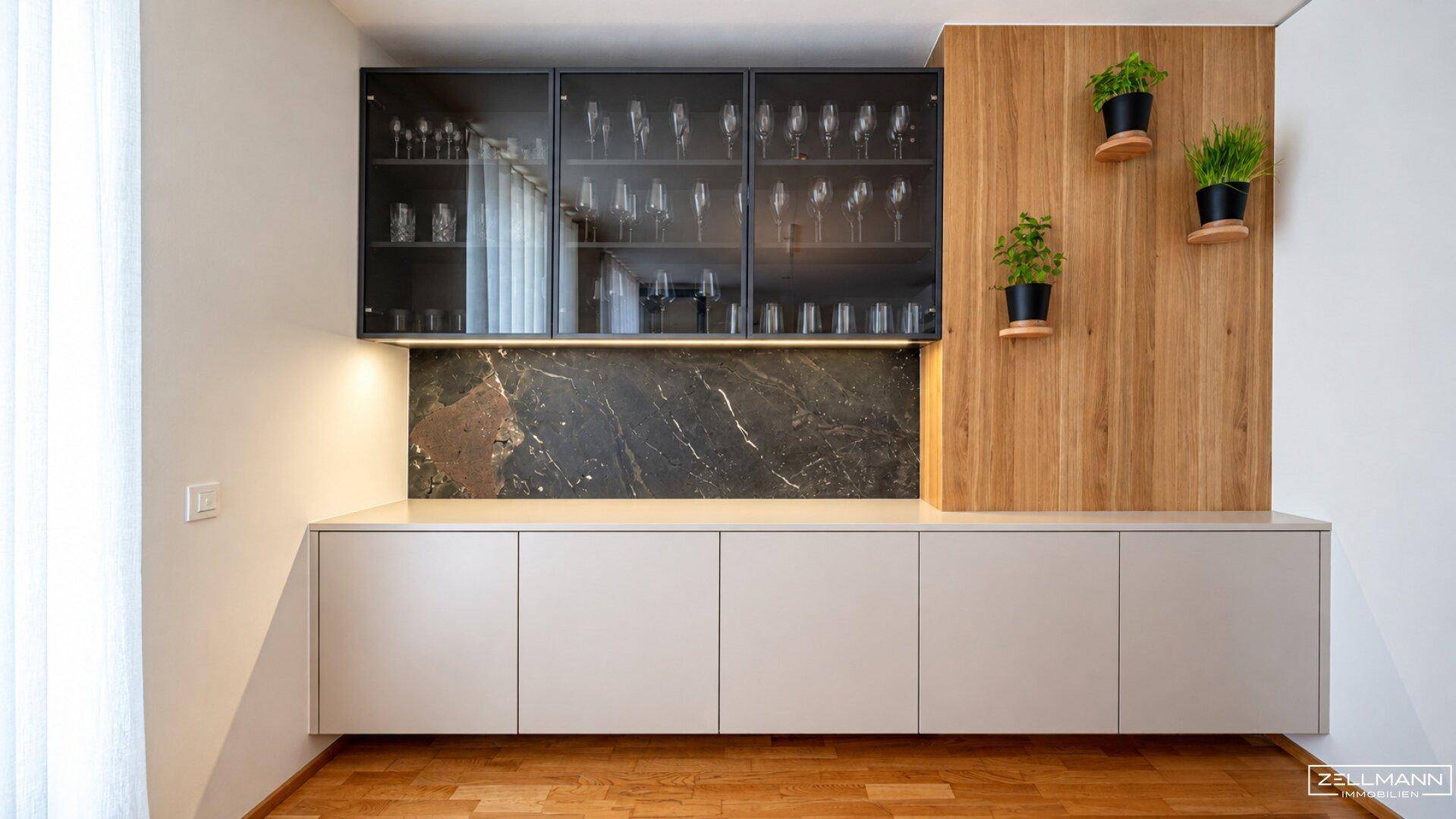 Elegantes Sideboard mit Glasvitrinen, dunkler Marmorplatte und Holzakzenten mit frischen Pflanzen.