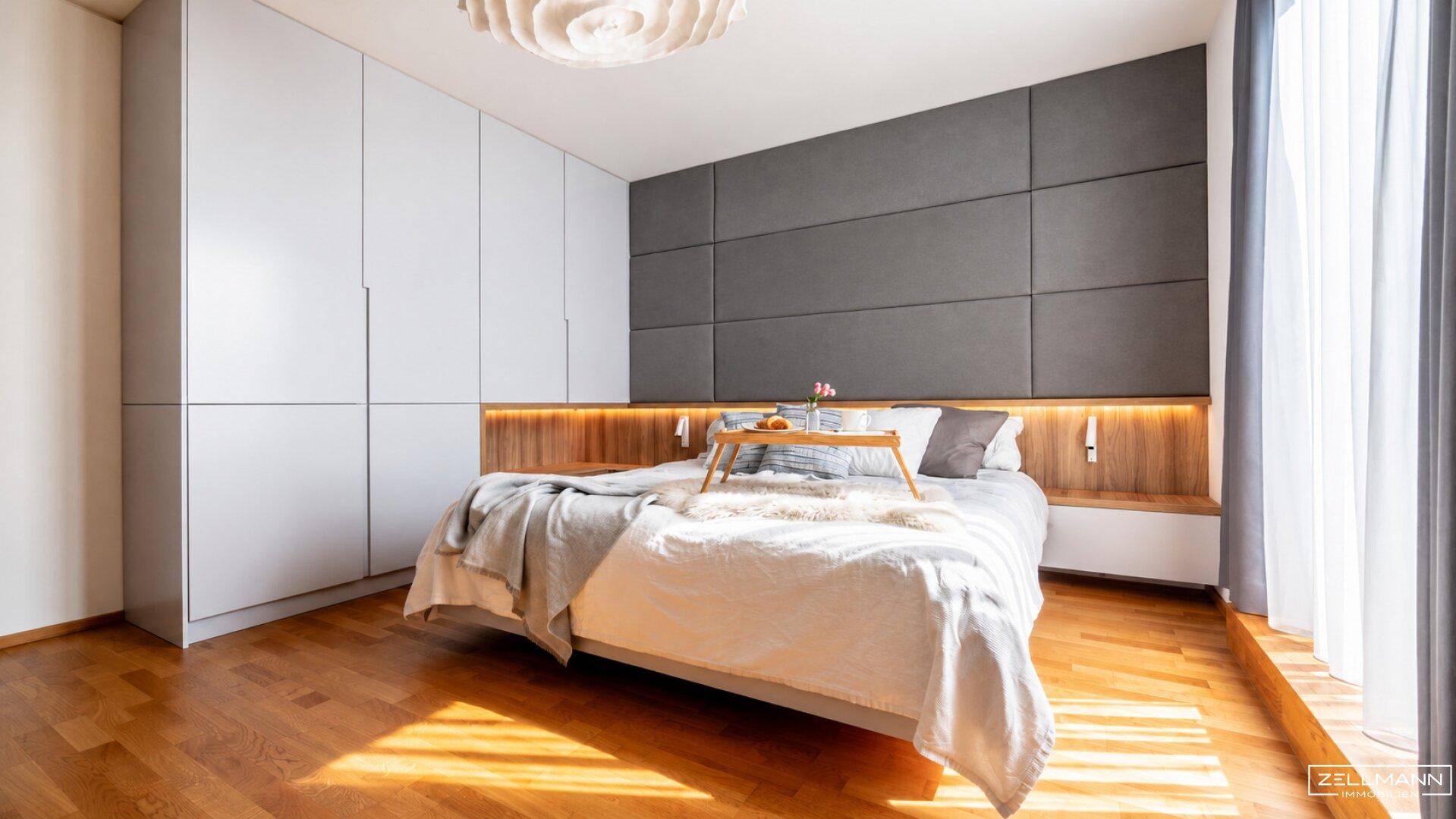 Modernes Schlafzimmer mit großem Bett, gepolstertem Kopfteil und integrierten Kleiderschränken.