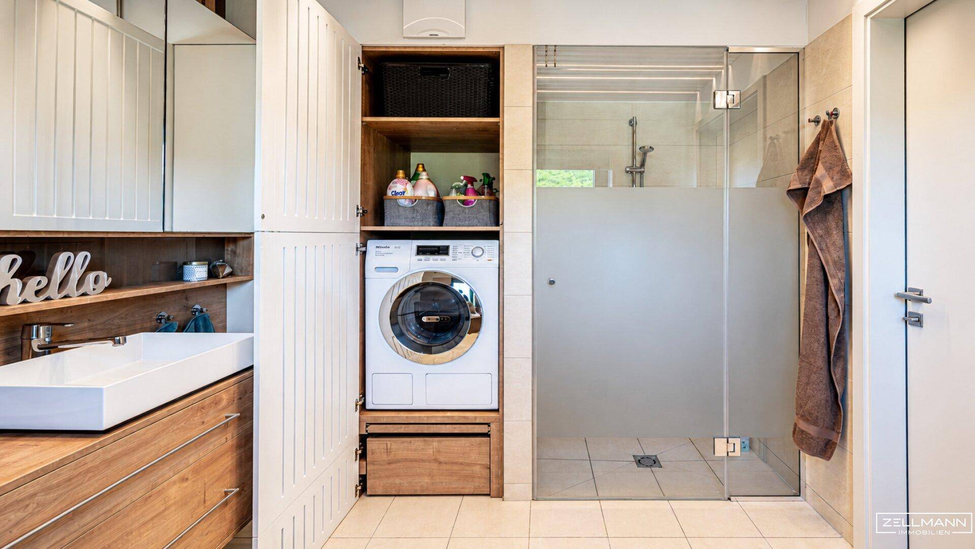 Praktischer Hauswirtschaftsraum mit Waschmaschine, Dusche und modernem Waschbecken.
