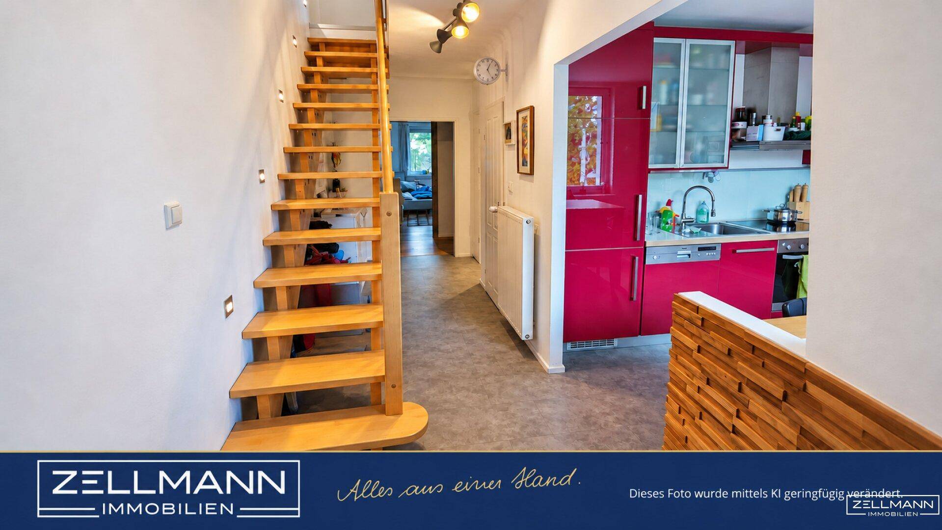 Eingangsbereich mit offener Holztreppe und direktem Zugang zur modernen Küche.