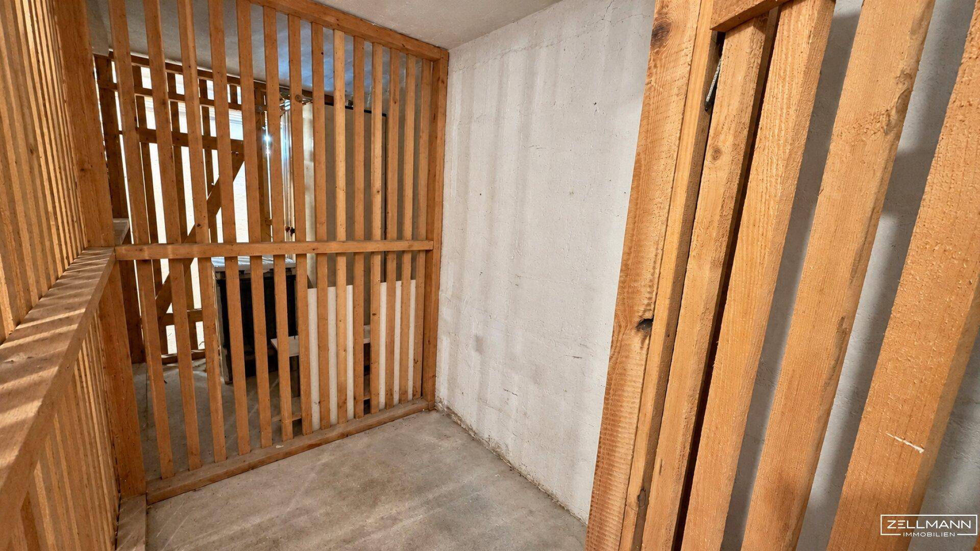 Abstellraum im Keller mit Holzlattenwänden und Betonboden, ideal für zusätzlichen Stauraum.