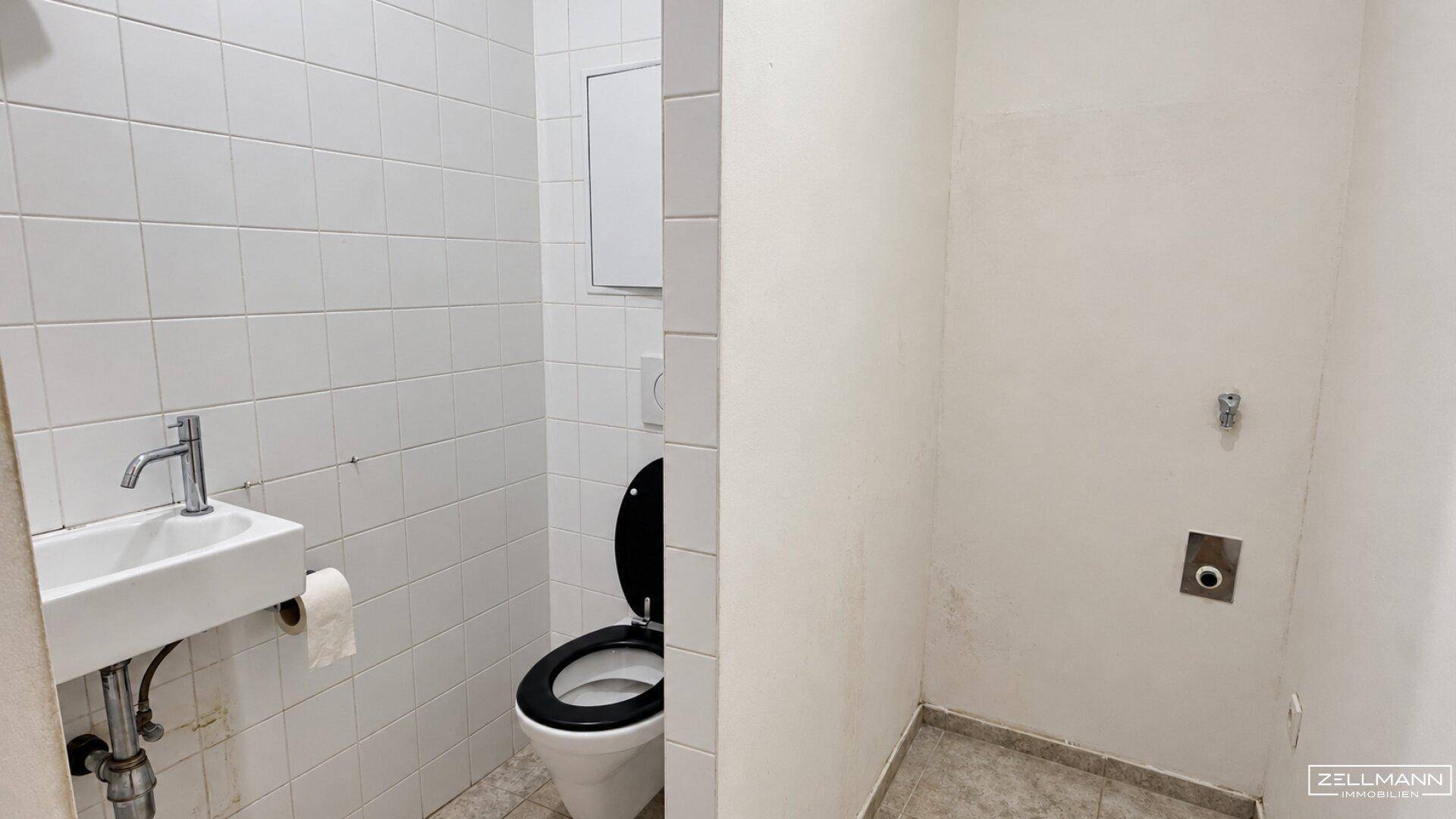 Kleines WC mit Waschbecken, Toilette und Anschlussmöglichkeiten für eine Waschmaschine.