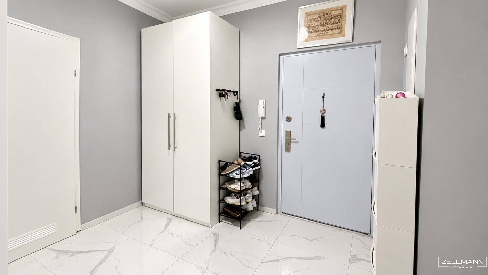 Eingangsbereich mit weißem Kleiderschrank, Schuhregal und Sicherheitstür.