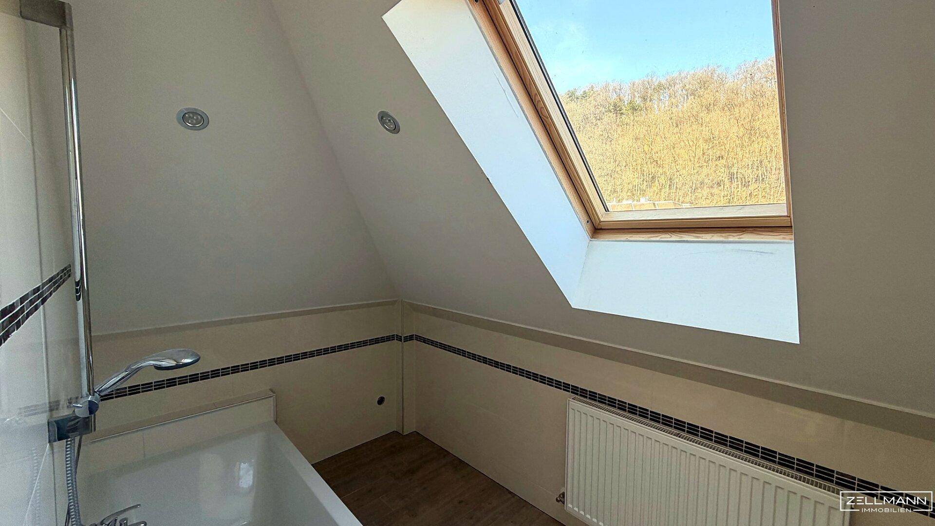 Badezimmer im Dachgeschoss mit Dachfenster und Badewanne, bereit für die Fertigstellung.