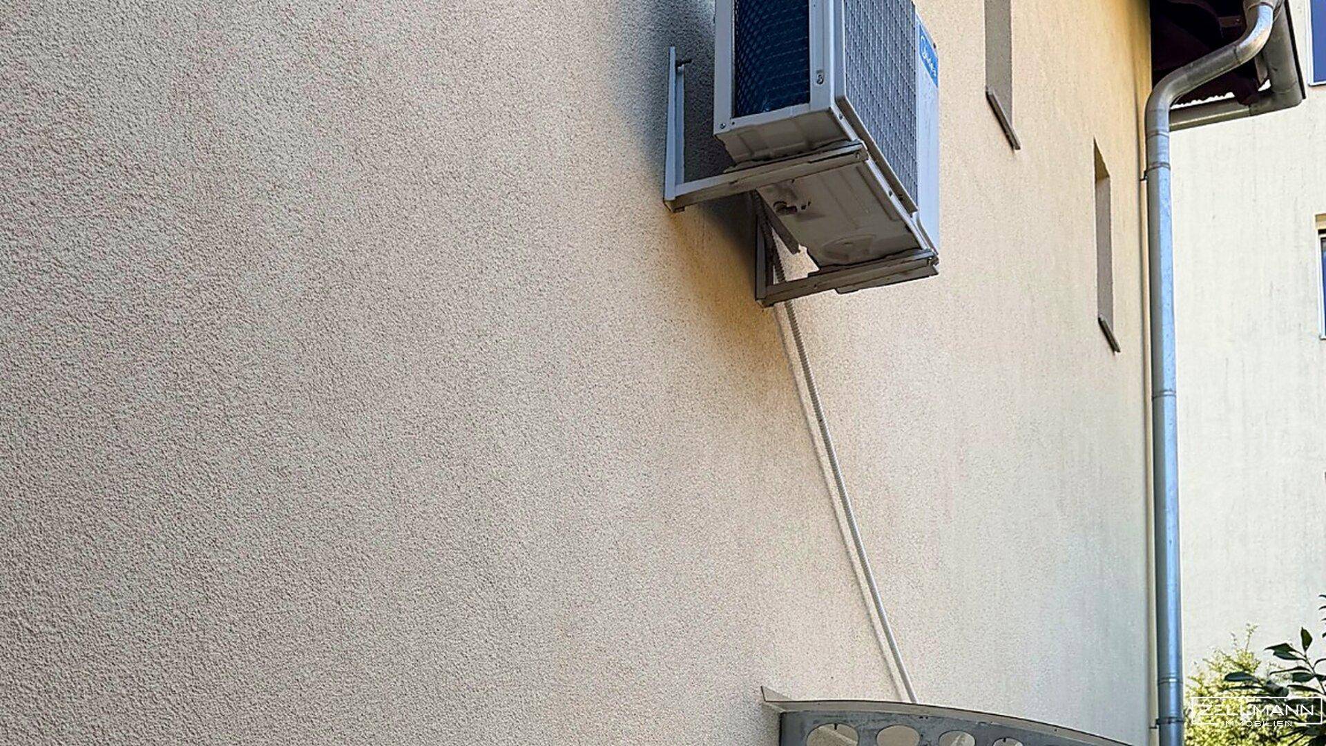 Außenansicht einer Klimaanlage an der Fassade eines Gebäudes mit Regenrinne.