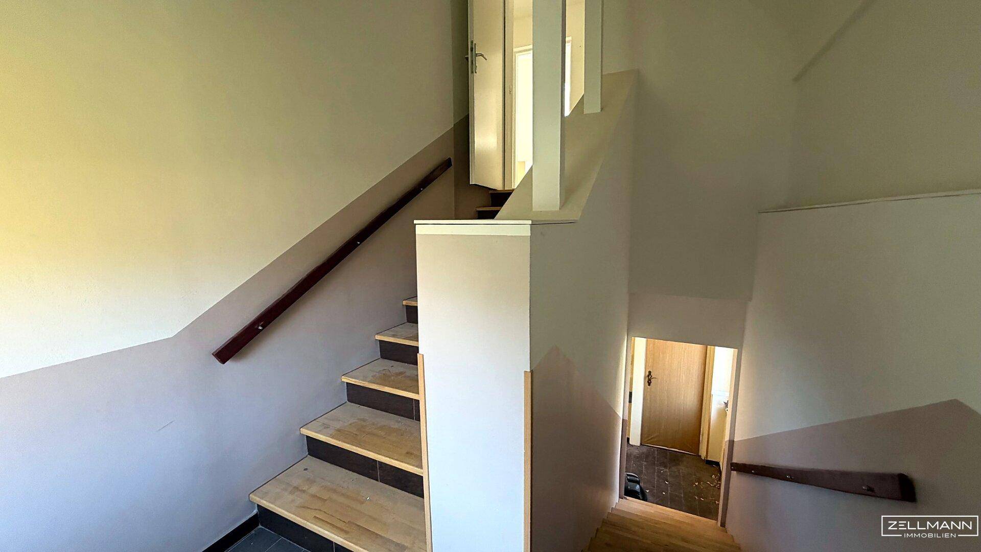 Treppenhaus mit Holzgeländer und mehreren Etagen, das die verschiedenen Wohnbereiche verbindet.