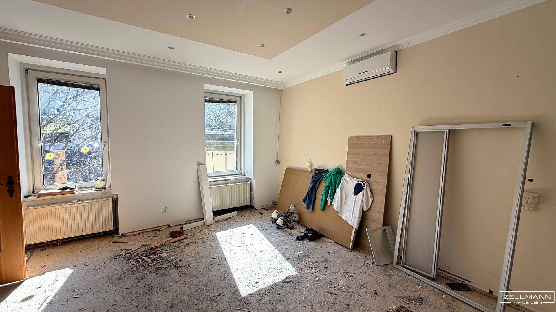 Helles Zimmer mit zwei Fenstern, Klimaanlage und Renovierungsbedarf, ideal als Schlafzimmer.