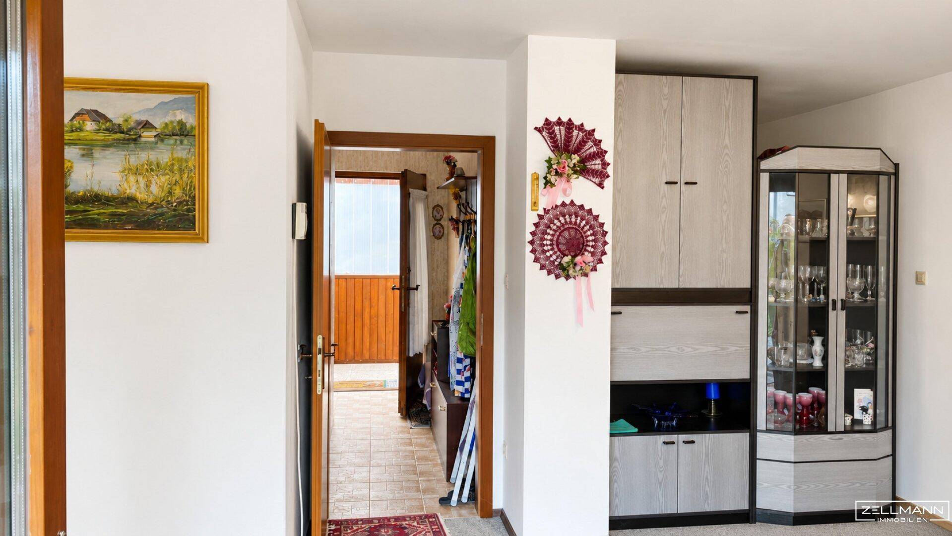 Heller Flur mit Holztür, einem Schrank und einer Vitrine, die den Eingangsbereich schmückt.