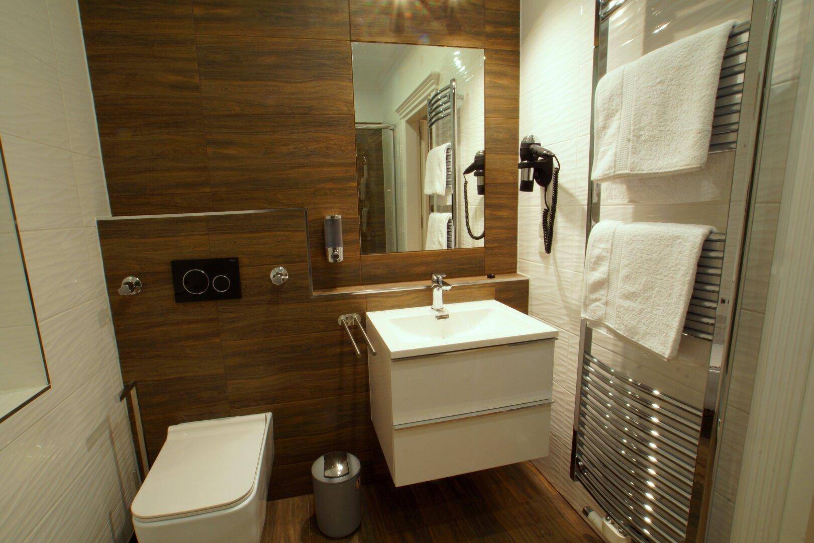 Modernes Badezimmer mit schwebendem Waschtisch, Wand-WC und Handtuchheizkörper.